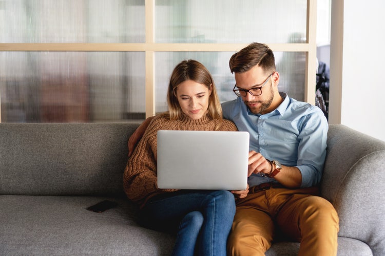 Prospective homebuyers reviewing a purchase agreement together on a laptop.