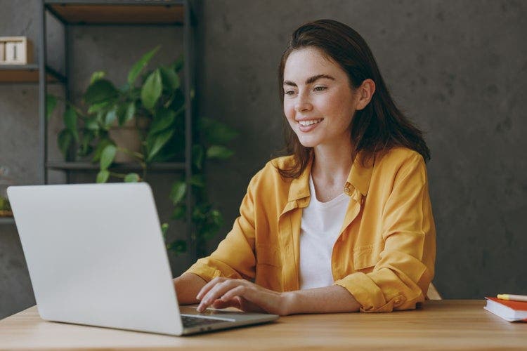 A woman sitting at a desk draws on a PDF on her laptop.