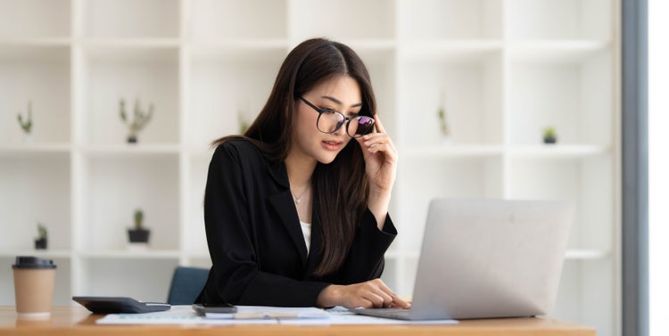 A woman sitting at a desk makes a PDF read-only on her laptop.