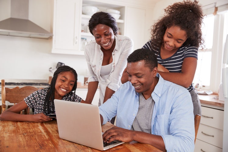 A man and his family create a shared family to-do list on a laptop.