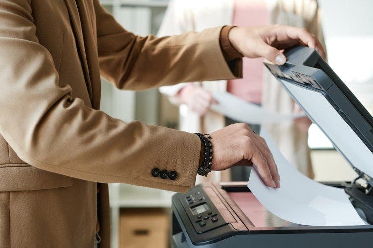 A man scans multiple pages into one PDF using a scanner.