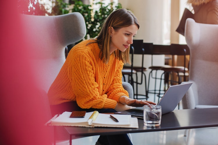 A woman uses a laptop to send a secure PDF with Adobe Acrobat.