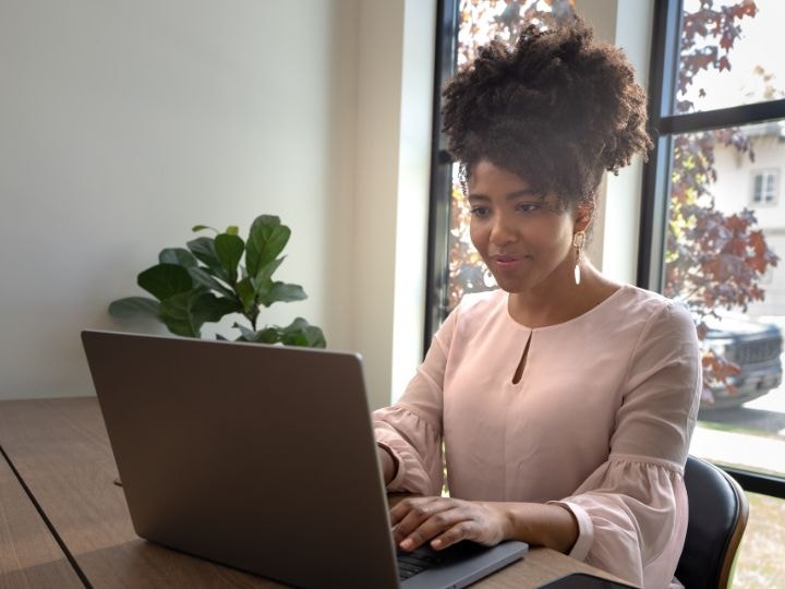 An image of a person sitting at a desk working on a laptop computer.