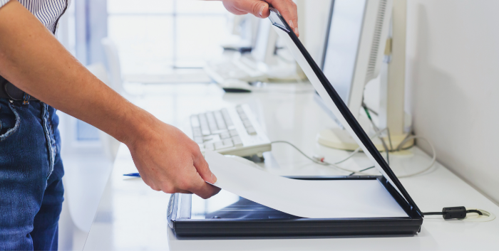 A man puts a piece of paper into a digital scanner