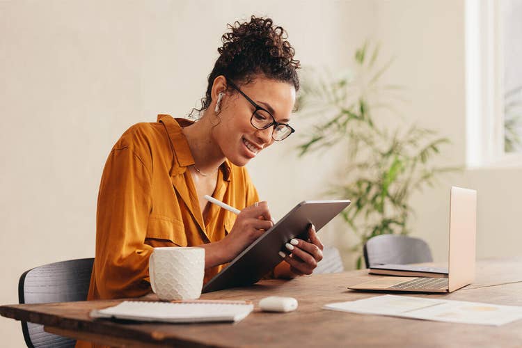 A homeowner sitting at a table filling out information for a real estate contract on their tablet device