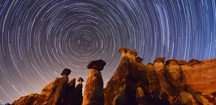 Looking up at rocky mountain with star trails behind it