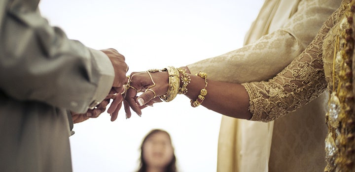 Bokeh wedding shot of a bride receiving her ring from the groom.