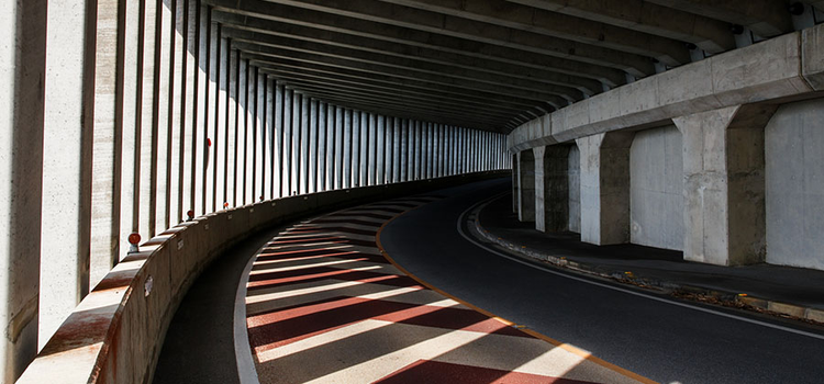 Highlights and shadows created by sunbeams passing through columns of a covered roadway