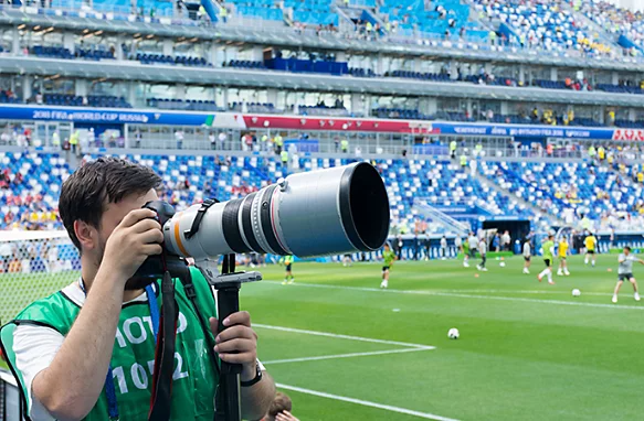 A photo of a sports photographer taking a photo at a soccer game.