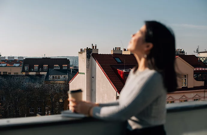 A photo of a standing person out of focus with buildings in focus in the background displaying improper lens calibration