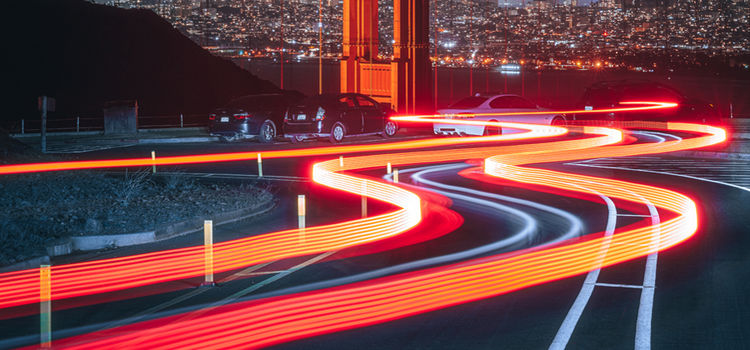 Light trails hovering over a city street from cars driving through