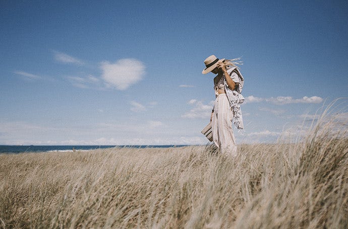 Practicing the rule of thirds taking a picture of a woman standing in a field near the ocean