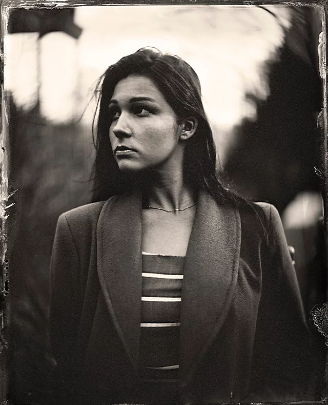 A vintage portrait photo of a person standing and looking to the left