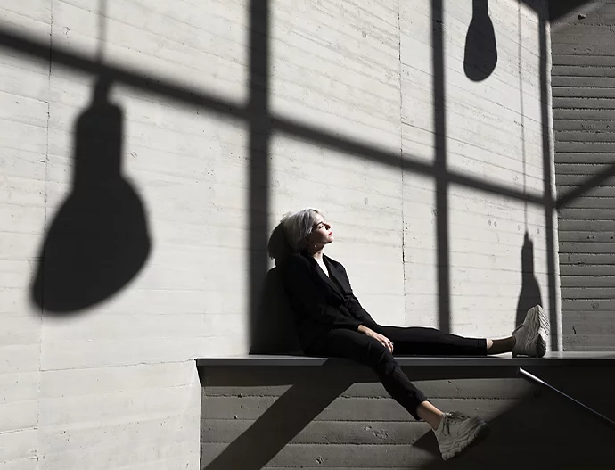 An example of shadow-photography where a person is sitting against a wall with shadows of lamps above them