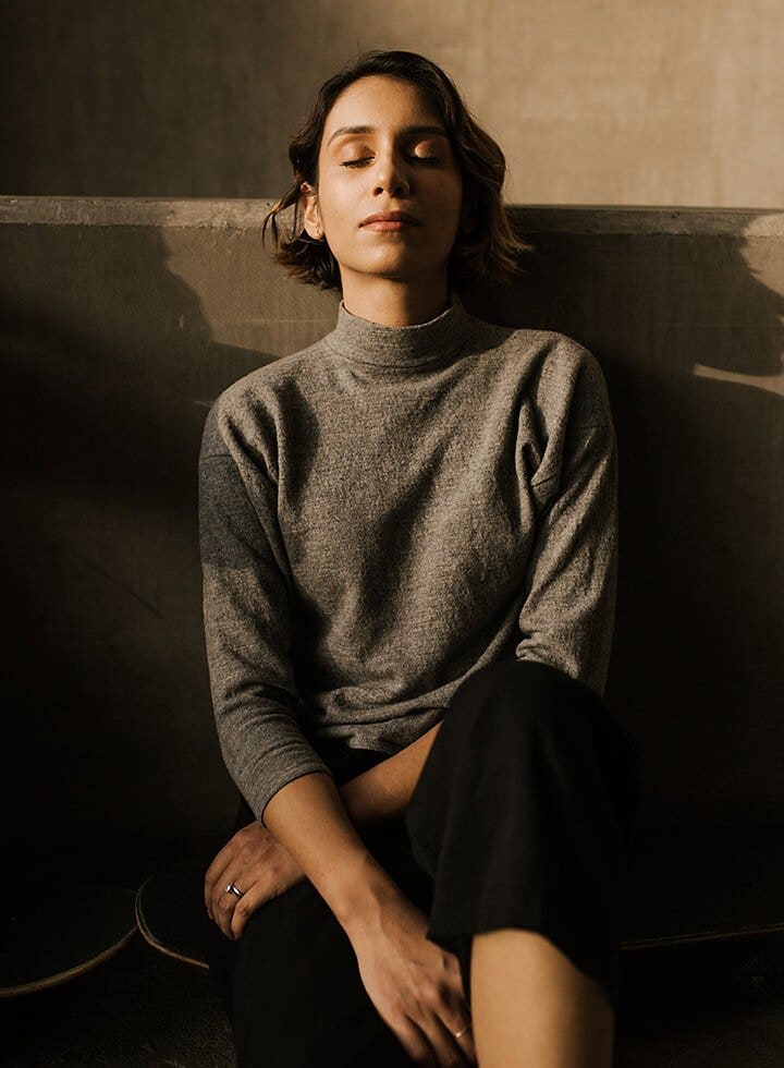 Model captured leaning against a concrete wall among shadows created by the portrait lighting