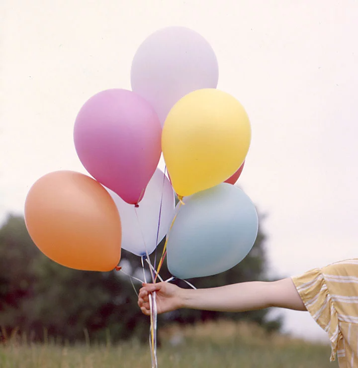 A hand holding an assortment of balloons