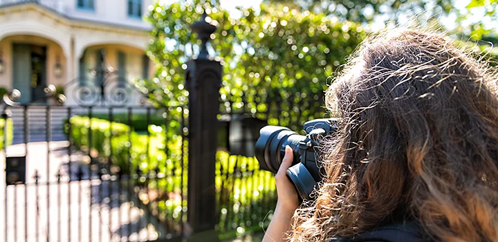 A photo of a real estate photographer taking an exterior photo of a home.