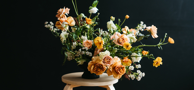 Bouquet of flowers on an end table lit with a spotlight in front of a black background