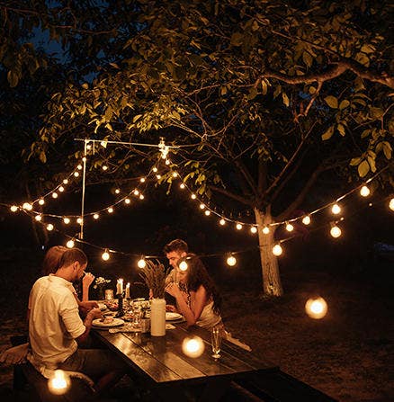 Capturing an image, at night, of the lIghts strung over a picnic table