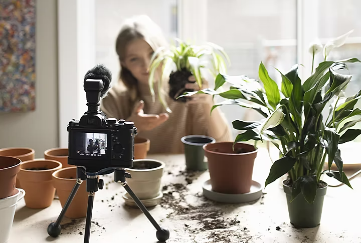 Person, die sich selbst für ihren Vlog zum Eintopfen von Pflanzen filmt