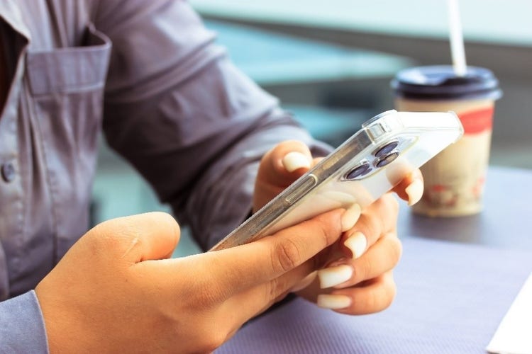 Professional woman holding an iPhone while sat at a café