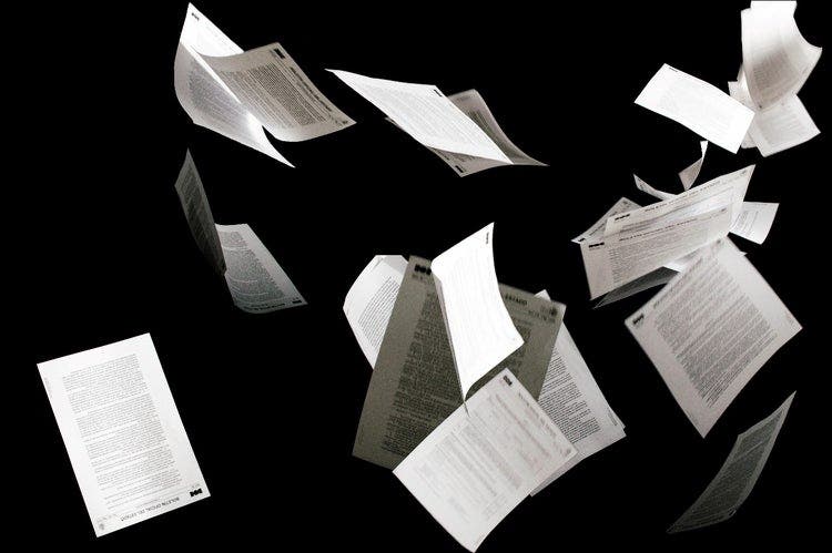 Pages of documents flying through the air on a black background.