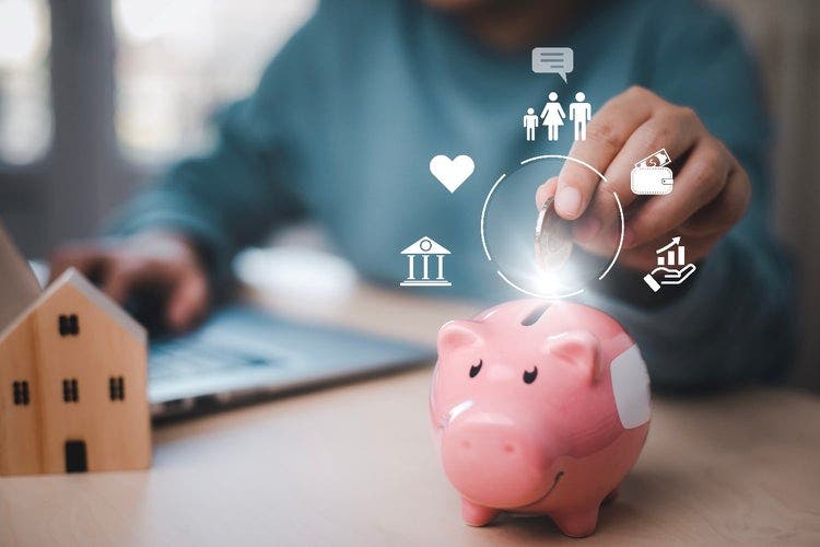 Person sitting at a table with a laptop and putting a coin into a piggybank. Icons overlaying the photo depict a a family, love, wallet with money, bank, and hand holding hold bar graph showing increased growth.