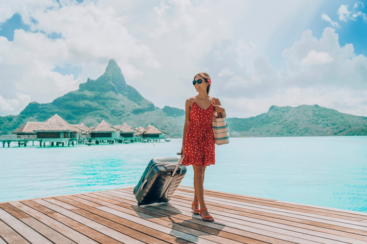 Photo of a woman on a cruise ship excursion at a beach resort with an overnight luggage.