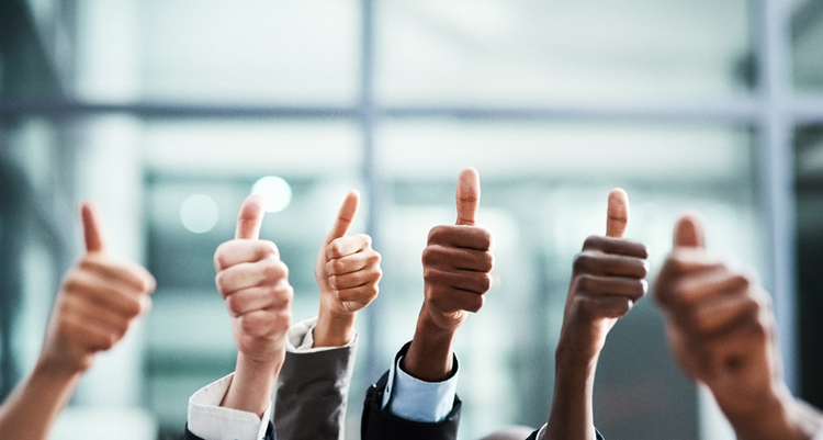 Photograph of six hands raised in the air giving the thumbs up sign.