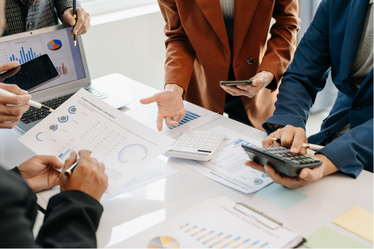 Four professionals at a desk, examining data on papers and devices, highlight the need for improved internal systems.