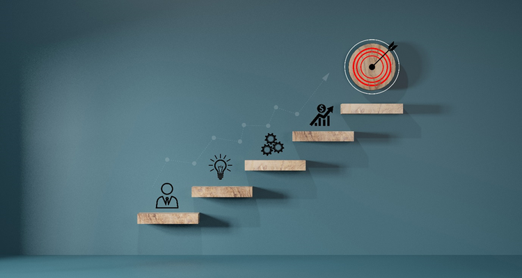 Conceptual image of moving up blocks to reach a goal. The images depicted at each stage include people, ideas, processes, targets, and reaching the ultimate goal.