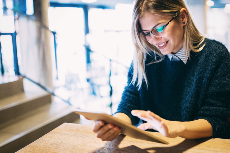 A professional woman smiles as she views the content on her tablet screen.