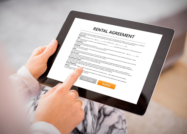 Person with a finger poised above Agree/Decline buttons on a Rental Agreement displayed on a tablet.