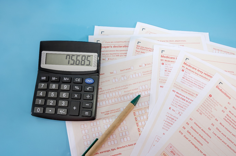 Paper copies of Australian annual tax forms with a pen and calculator.