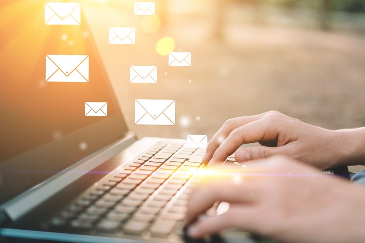 Woman on a laptop with email symbols floating