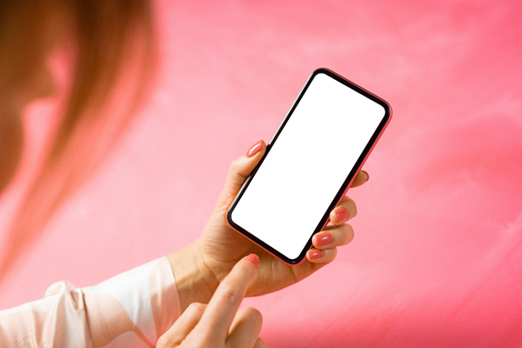 A person using an iPhone against a pink background.