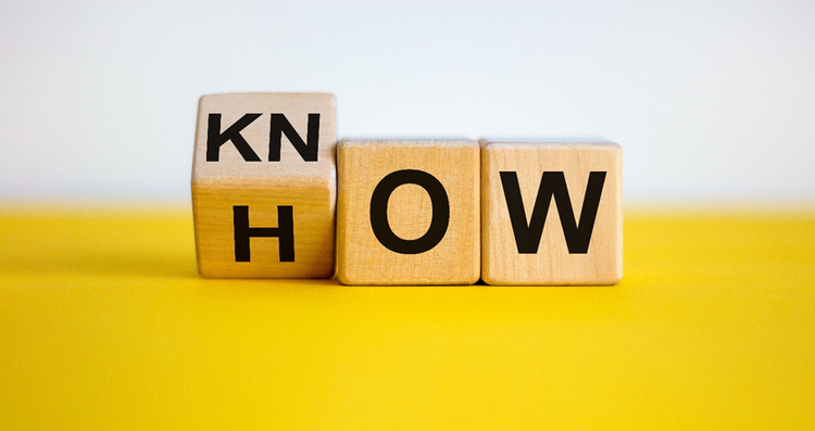 Letters written on wooden cubes rotated partially to change from reading as "How" to "Know how".