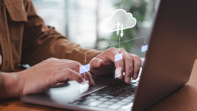 Photo of a man’s hands on the keyboard of a laptop. A conceptual diagram over the photo depicts the concept of using a cloud based storage system to collaborate on documents.