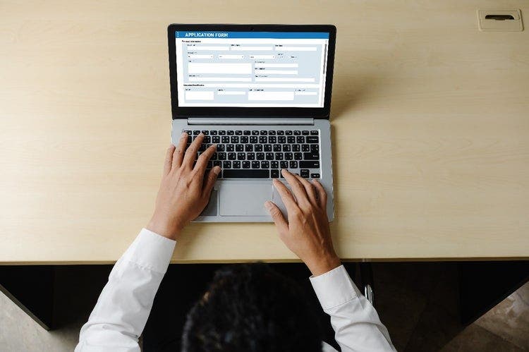 Photo of a person sitting at a desk completing an online application form.