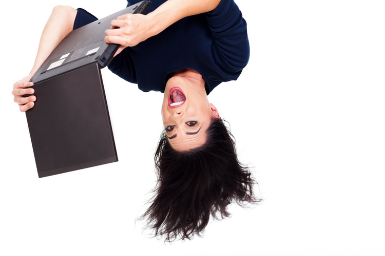 Photo of a woman upside down with an open mouth using a laptop.