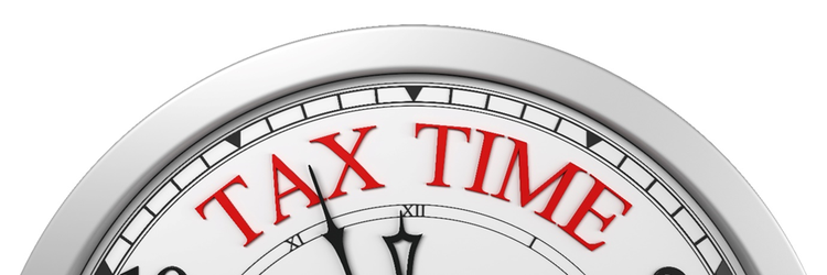 Top portion of roman numeral clock face with roman numerals and the words tax time with the hands on the clock nearing 12: 00 o'clock.