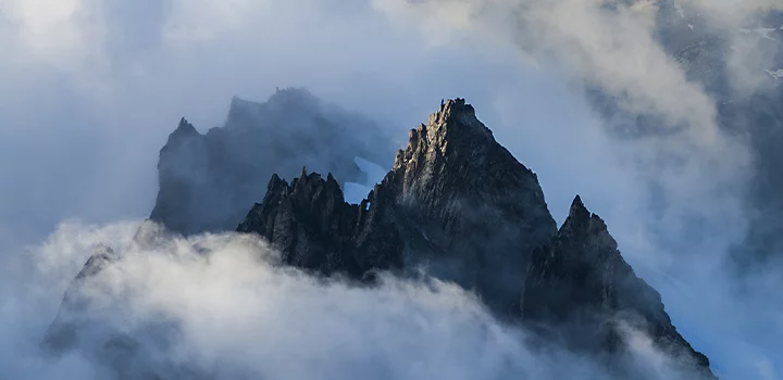 A mountainscape peering through clouds