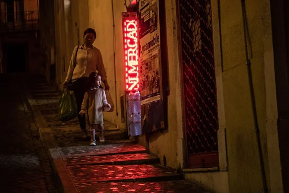 A photo of a parent and child walking down a sidewalk at night.