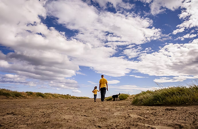 Wide angle photo of a person walking with their child and dog