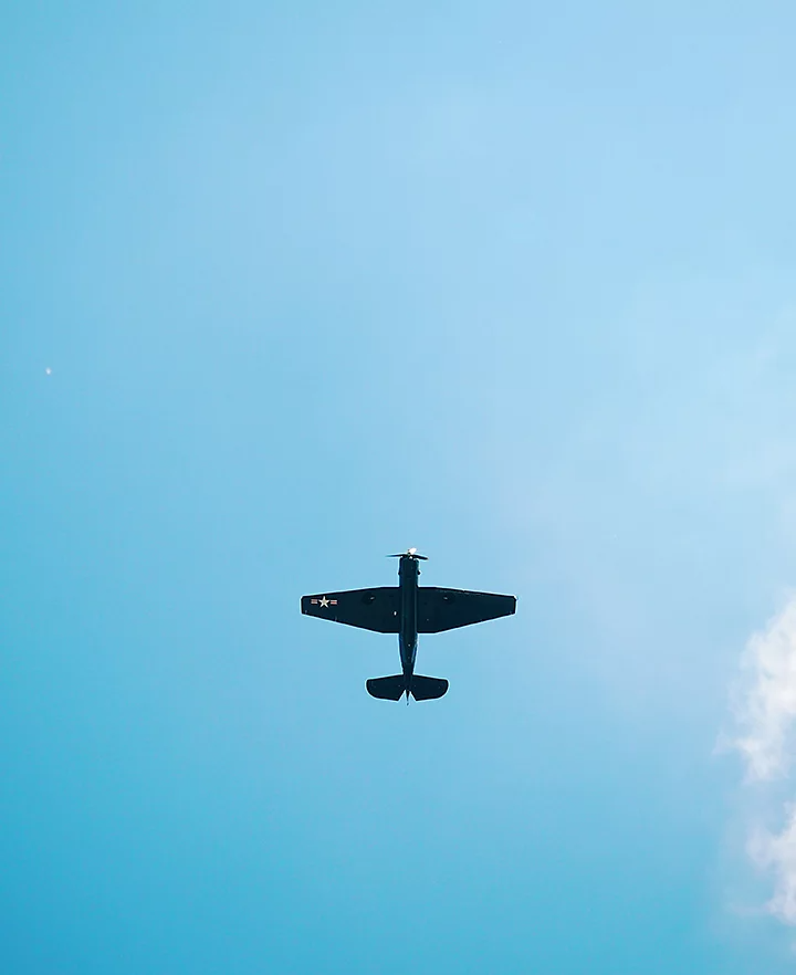 Looking directly up at the bottom side of a old fighter jet flying in the sky