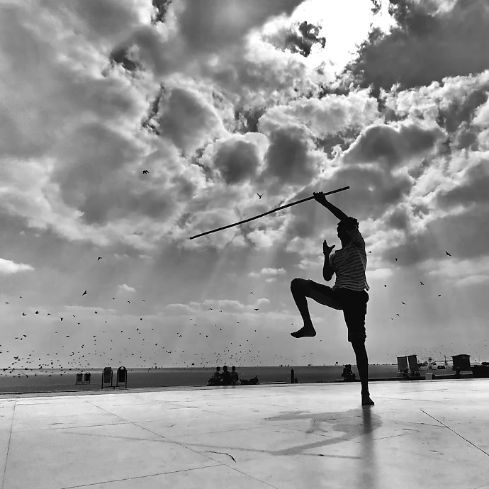 Black-and-white photo of a person practicing martial arts with a stick