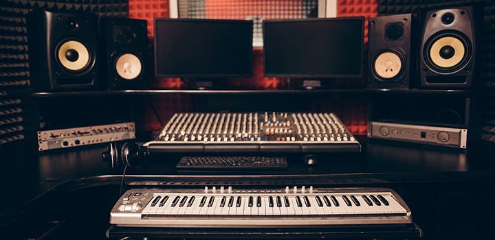 Recording studio with audio equipment and piano arranged.