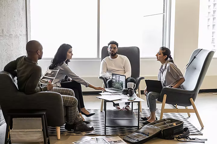 Photograph of four adults engaged in a discussion about matte painting sitting around a table