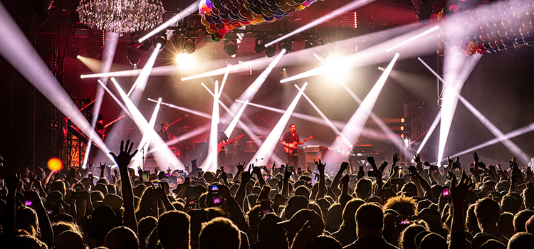 A crowd of people in front of a stage of a band playing music