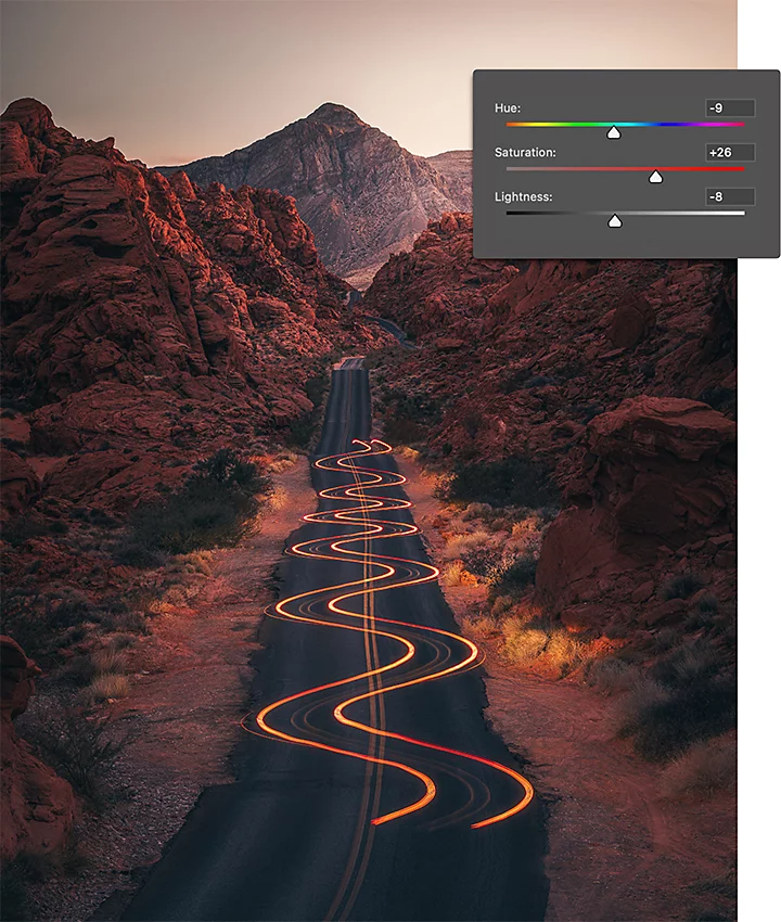 Light trails hovering over a rocky desert roadway from a car driving through